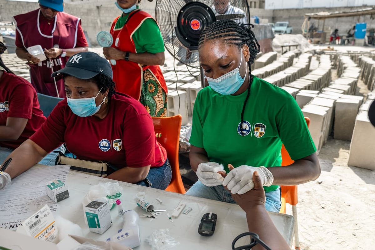 Two clinicians at a table with testing kits and a blood glucose meter.