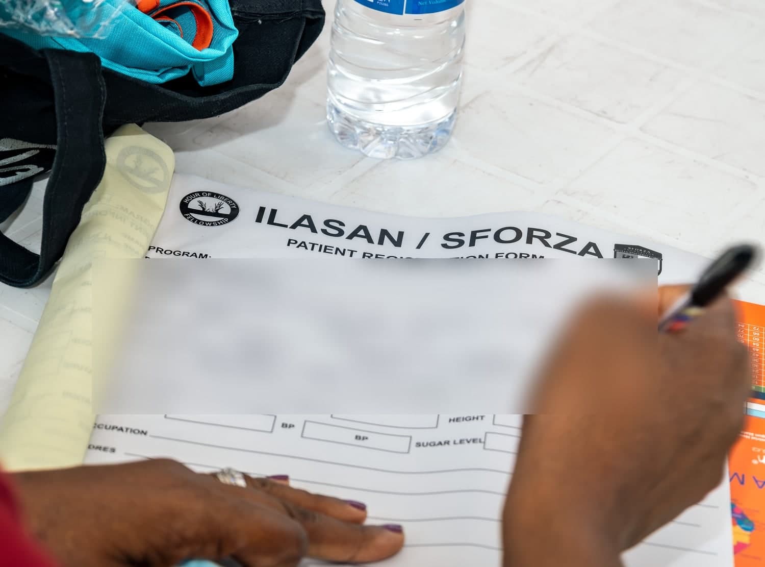 A patient registration form headed Ilasan slash Sforza, being completed by hand, with fields for temperature, blood group, blood pressure and sugar level.